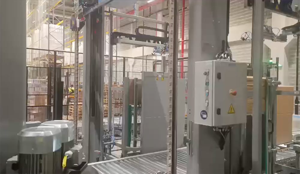 Sorsa's automatic paper corner protector placement system integrated into a pallet strapping line.