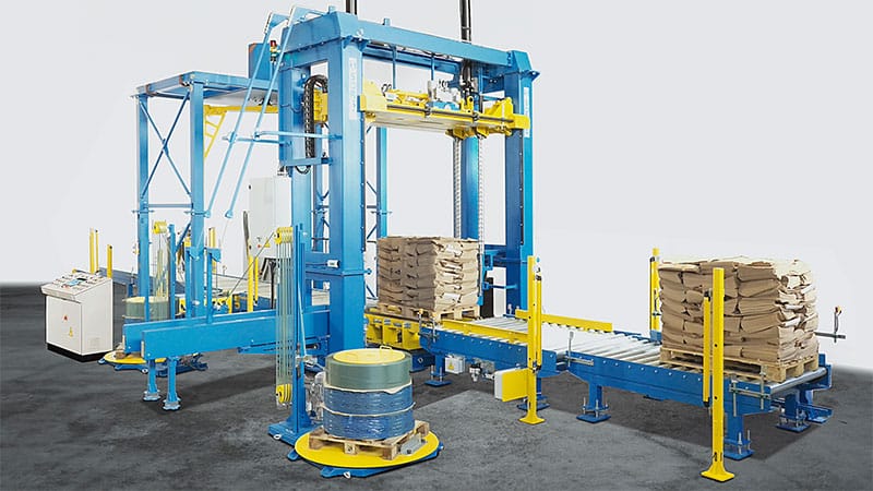 Línea automática Sorsa FIP-800 realizando compresión y flejado de un palet de sacos de papel.